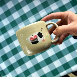 Kubek Krówki wśród stokrotek