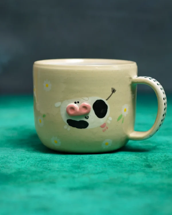 Kubek krówki wśród stokrotek