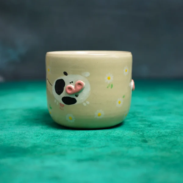 Kubek krówki wśród stokrotek