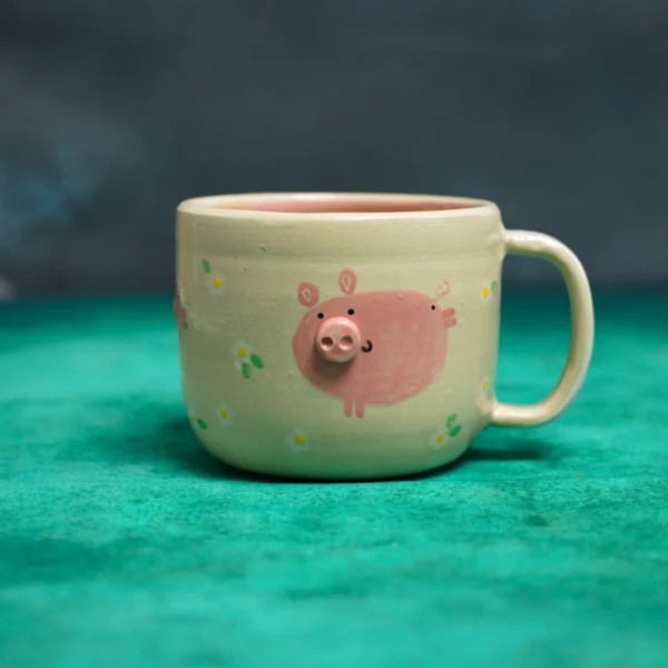 Kubek Świnki wśród stokrotek