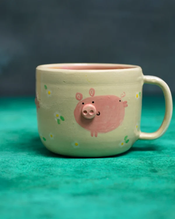 Kubek Świnki wśród stokrotek