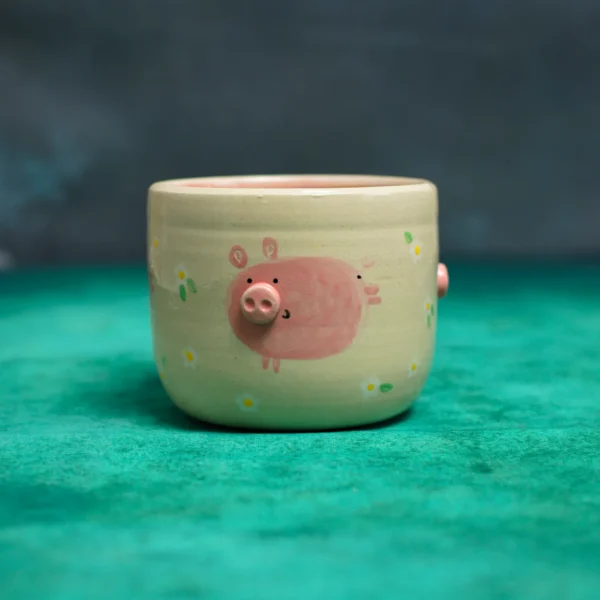 Kubek Świnki wśród stokrotek