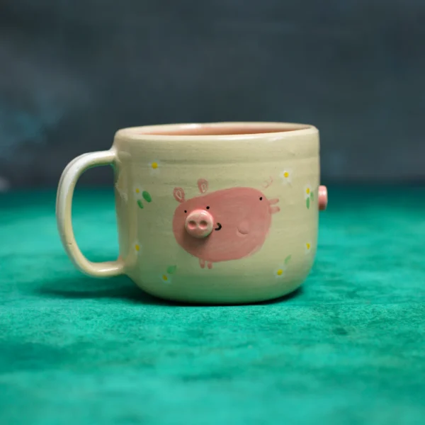 Kubek Świnki wśród stokrotek