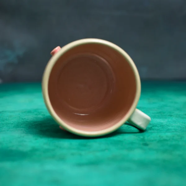 Kubek Świnki wśród stokrotek